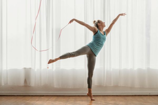 Person doing rhythmic exercises in a minimal white studio.